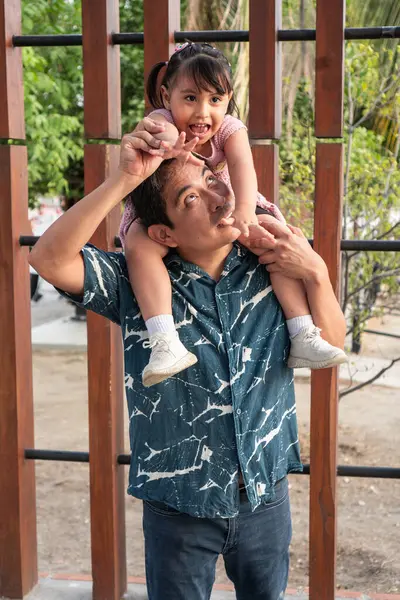 Aborjin İspanyol baba, neşeli kızını omuzlarında taşırken, komik suratlar yapıyor.