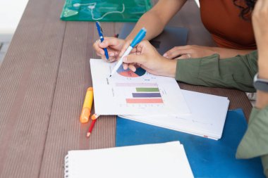 Üniversite öğrencileri bir projede işbirliği yapıyor, kampüste grafikleri ve grafikleri birlikte analiz ediyorlar.