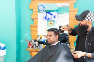 Kuaför, kuaförde müşterinin saçını tarıyor.