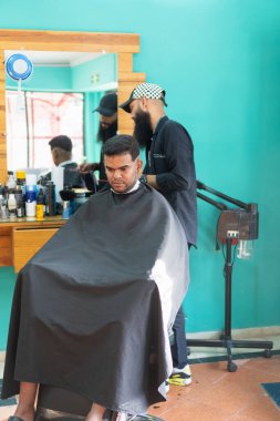 Kuaför kuaför kuaförde siyah pelerin giyen müşterinin saçını kesiyor.