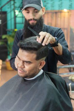 Kuaför müşteri saçlarını tarıyor, kuaförde yeni bir saç kesimine hazırlanıyor.