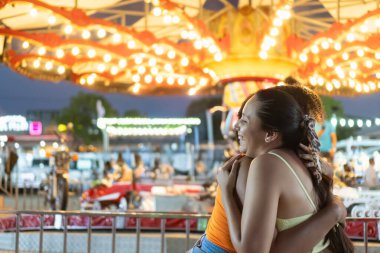 Canlı bir karnavalda iki arkadaş neşeli bir kucaklaşmayı paylaşıyor.