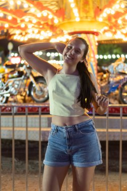 Neşeli bir karnaval gezisinin önünde poz veren gülümseyen kadın.