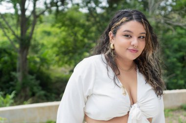 Kıvrımlı manken, kendine güvenen bir şekilde poz veriyor, vücudun pozitifliğini ve modadaki çeşitliliği gösteriyor.