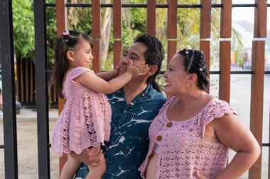 Kızı babasının yüzüne dokunuyor, anne babasıyla samimi bir anı paylaşıyor.