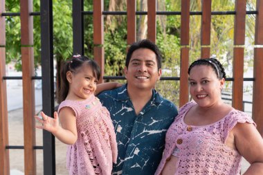 Neşeli bir yerli ailenin portresi, baba, hamile anne ve kız, açık havada eğleniyorlar.