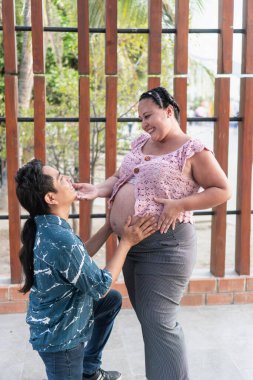 Mutlu İspanyol çift bebek bekliyor, koca hamile karısının karnına dokunuyor.