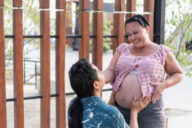 Mutlu İspanyol çift bebek bekliyor, koca hamile karnına dokunuyor.