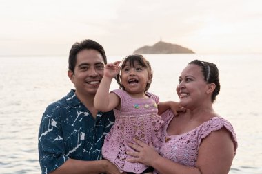 Gülümseyen yerli İspanyol ailesi gün batımında güzel bir plaj tatilinin tadını çıkarıyor.