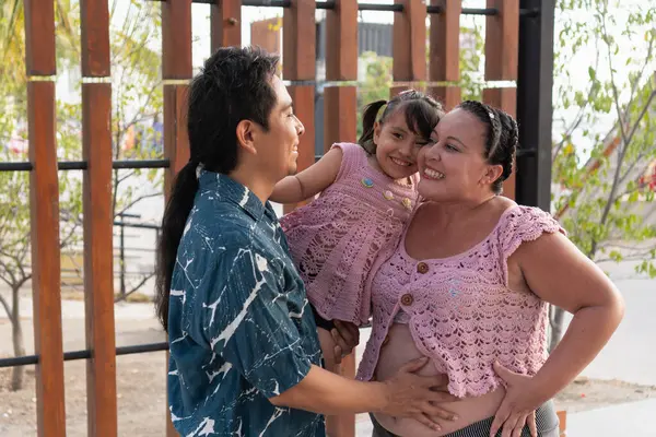 Mutlu İspanyol ailesi yeni bir bebek bekliyor ve küçük kızlarını parkta tutuyorlar.