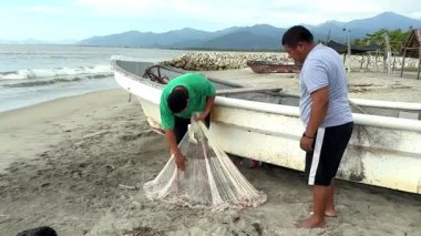 Balıkçılar birlikte çalışır, teknelerinin yanındaki plaja balık ağı çekerler.