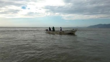 Bir teknede çalışan balıkçılar, balıkçı ağı çekiyorlar.