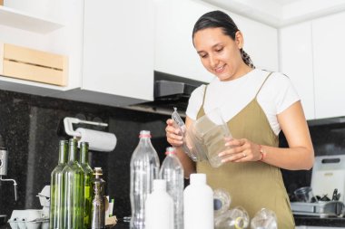 Ev hanımı geri dönüşüm için mutfakta plastik ve cam şişeleri ayırıyor.