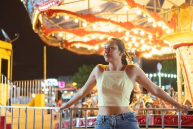 Canlı bir gece karnavalında atlı karıncanın yanında dinlenen bir kadın.