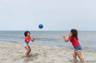 Genç kızlar kumsalda top oynuyorlar Yaz tatilinin tadını çıkarıyorlar