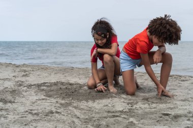 Kumsalda kumdan kale inşa eden iki kız çocukluklarının tadını çıkarıyor.