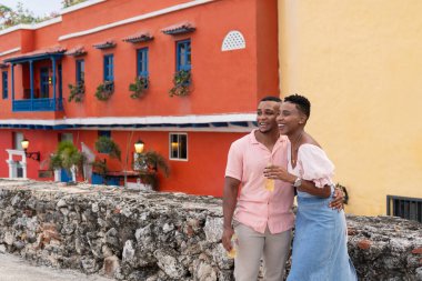 Genç çift, tarihi şehir duvarında sarılıyor, gülüyor ve içiyor.