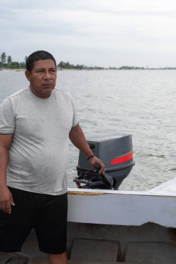 Küçük bir teknenin dümencisini tutan adam, kıyı sularında yüzüyor.