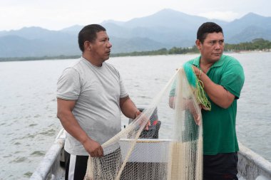 İki Latin Amerikalı balıkçı teknelerinde balık tutmak için ağ hazırlıyor.