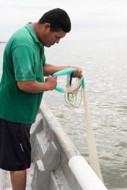 Balıkçı, küçük teknesinden bir ağ hazırlıyor.