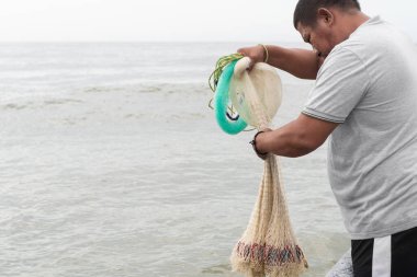 Balıkçı oltayı tutuyor, balık tutmak için suya atmaya hazırlanıyor.