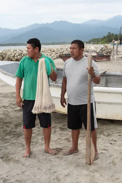 İki Latin Amerikalı balıkçı tekneleriyle kumlu sahilde çalışmaya hazırlanıyor.
