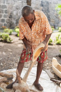Adam ustalıkla ahşabı geleneksel bir objeye oyuyor ve zanaatkar sanatını gösteriyor.