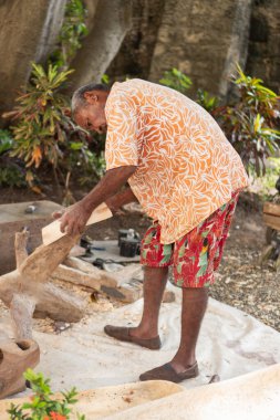İnsan elle ahşap oyuyor, açık havada heykel yapıyor.