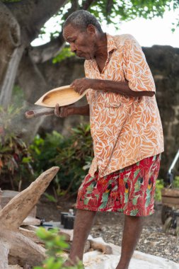Yaşlı bir zanaatkar el yapımı ahşap bir kâseyi zımparalıyor, toz yaratıyor, gelenek ve beceriyi simgeliyor.