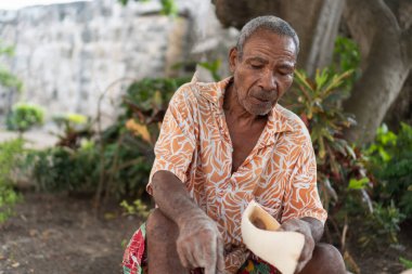 Yaşlı zanaatkar hindistan cevizi kabuğu oymaya odaklanıyor, gelenek ve beceriyi koruyor.
