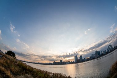 Arka planda mavi gökyüzü, bazı bitkiler ve Umeda şehri (Umeda, Osaka, Japonya) (2021220-019) ile nehir kenarı manzarası)