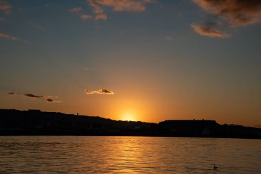 Gün batımının görüntüsü mavi gökyüzü ile denizi yansıtıyor