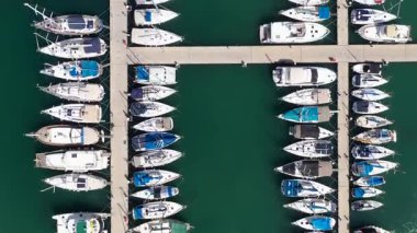 Küçük tekneler ve yatlar büyük bir marinada demirli, yukarıdan aşağıya hava manzaralı..