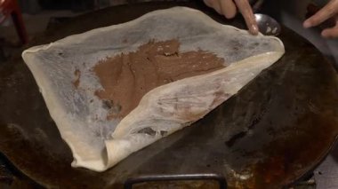 Satıcı çikolatalı, yuvarlak kremalı ekmek yapıyor.