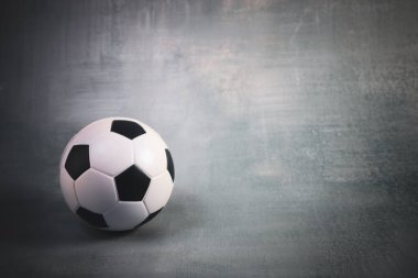 Gri bir duvara karşı yumuşak ışıkta bir futbol topu. Minimalist ve profesyonel, spor tasarımları, reklamlar ya da editör projeleri için mükemmel. Aktiviteyi, takım çalışmasını ve atletizmi simgeler..