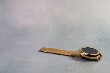 Unclasped gold smartwatch positioned in the lower-right corner on a textured gray background. Perfect for showcasing technology, luxury, and contemporary lifestyle themes. clipart