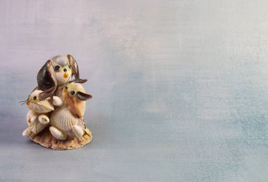 Açık gri dokulu bir arka fonun sol tarafına yerleştirilmiş, deniz kabuklarından yapılmış iki kedi yavrusuyla dekoratif bir köpek heykeli. Eşsiz tasarım, doğal ve sanatsal cazibeyi vurguluyor..