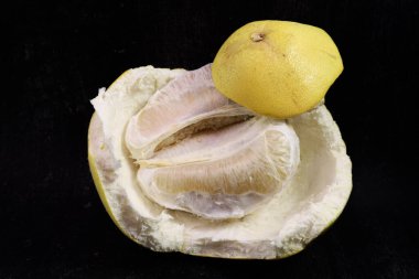 Siyah bir arka planda püre kabuğunun üzerinde taze bir parça püre var. Yemek fotoğrafçılığı ve turunçgiller için eşsiz bir kompozisyon..