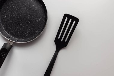 Üst görünüm kızartma tavası ve beyaz arkaplanda plastik kürek.