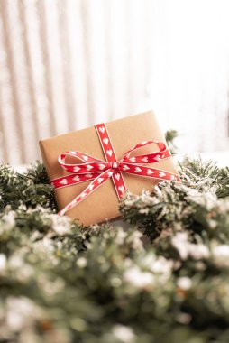 Kraft karton hediye kutusu. Gri ahşap arka planda kaba halatla bağlanmış. Noel ağacı dalları ve Noel süslemeleri var..
