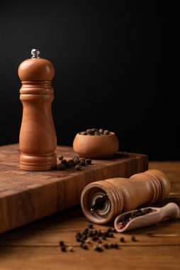 Karabiber değirmeni ve tüm biber kepçesiyle siyah masada. Üst görünüm.