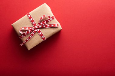 Aziz Sevgililer Günü dekorasyonunun en üst görüntüsü. Parlak pullar ve kırmızı kurdeleli el işi kağıt hediye kutusu..