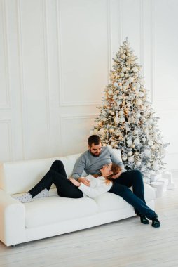 Noel ağacının yanında güzel bir çift sarılıyor. Yeni yıl atmosferi. İki insanın Noel ağacının yanında şefkatle sarılıyorlar..