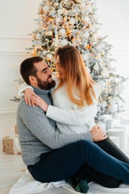 Noel ağacının yanında güzel bir çift sarılıyor. Yeni yıl atmosferi. İki insanın Noel ağacının yanında şefkatle sarılıyorlar..