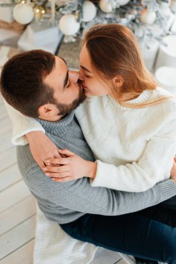 Noel ağacının yanında güzel bir çift sarılıyor. Yeni yıl atmosferi. İki insanın Noel ağacının yanında şefkatle sarılıyorlar..