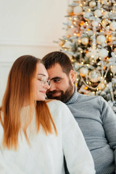 An attractive couple near Christmas tree and hugging. New Years atmosphere. Tender hugs near the Christmas tree of two people.