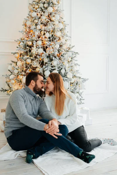 An attractive couple near Christmas tree and hugging. New Years atmosphere. Tender hugs near the Christmas tree of two people.