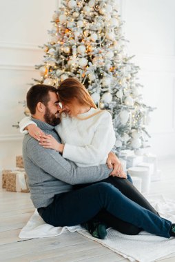 Birbirine aşık bir çift, Noel ağacının iç tarafındaki Noel ağacının yanında kışın evde Noel tatilinde sarılıp öpüşüyor. Bir erkek ve bir kadın birlikte yeni yılı kutluyorlar.