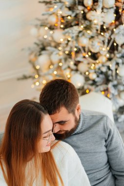 Birbirimize, Noel, yeni yıl ağacı yakınındaki kanepede oturan hafifçe gülümseyerek aşık bir çift.