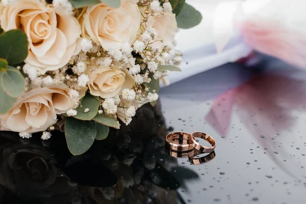 在一束鲜花的衬托下 一幅带有结婚戒指的美丽而柔和的照片映衬在黑色的表面 免版税图库照片